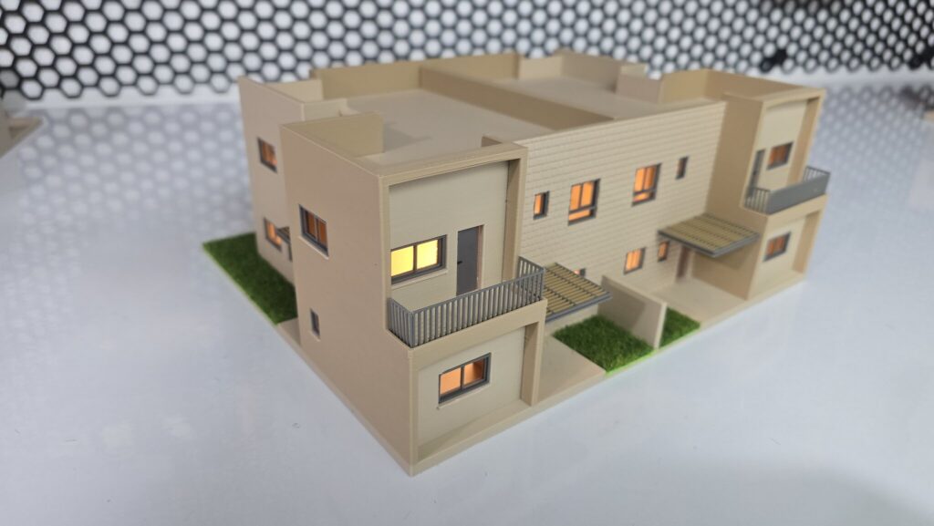 דגם אדריכלי מואר של שני בתים צמודים על שולחן