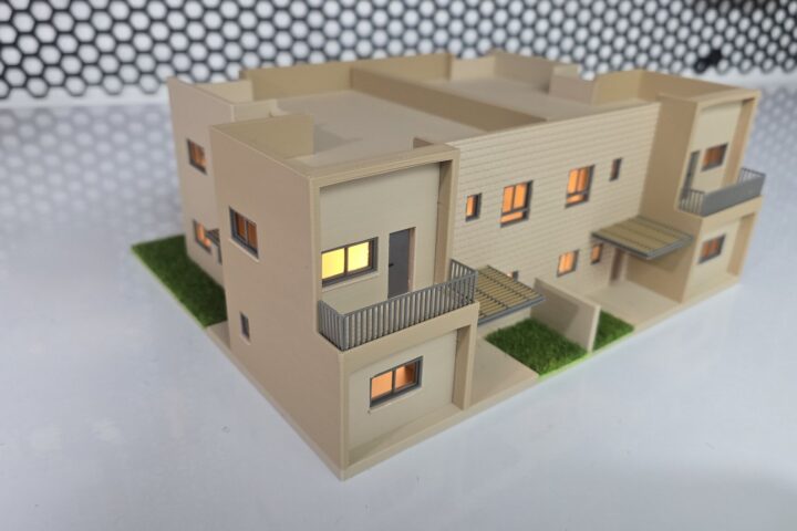 דגם אדריכלי מואר של שני בתים צמודים על שולחן